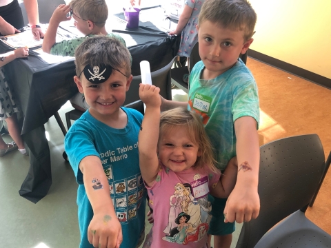 Young program participants posing with an eyepatch and pirate temporary tattoos. 