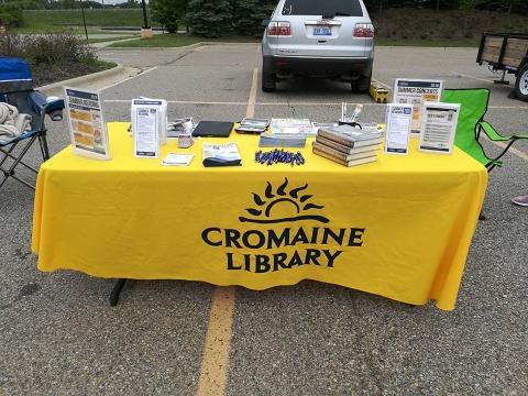 A table set up at the Farmer's Market with Cromaine tablecloth, pamphlets, and giveaway items. 
