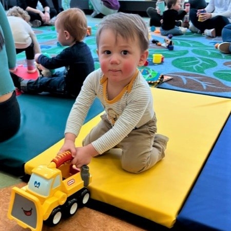 A baby playing with a toy truck. 